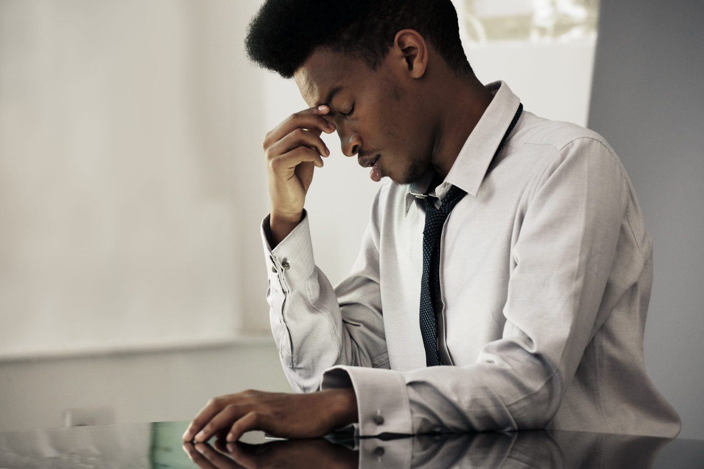 A young man sits in his office, looking stressed out