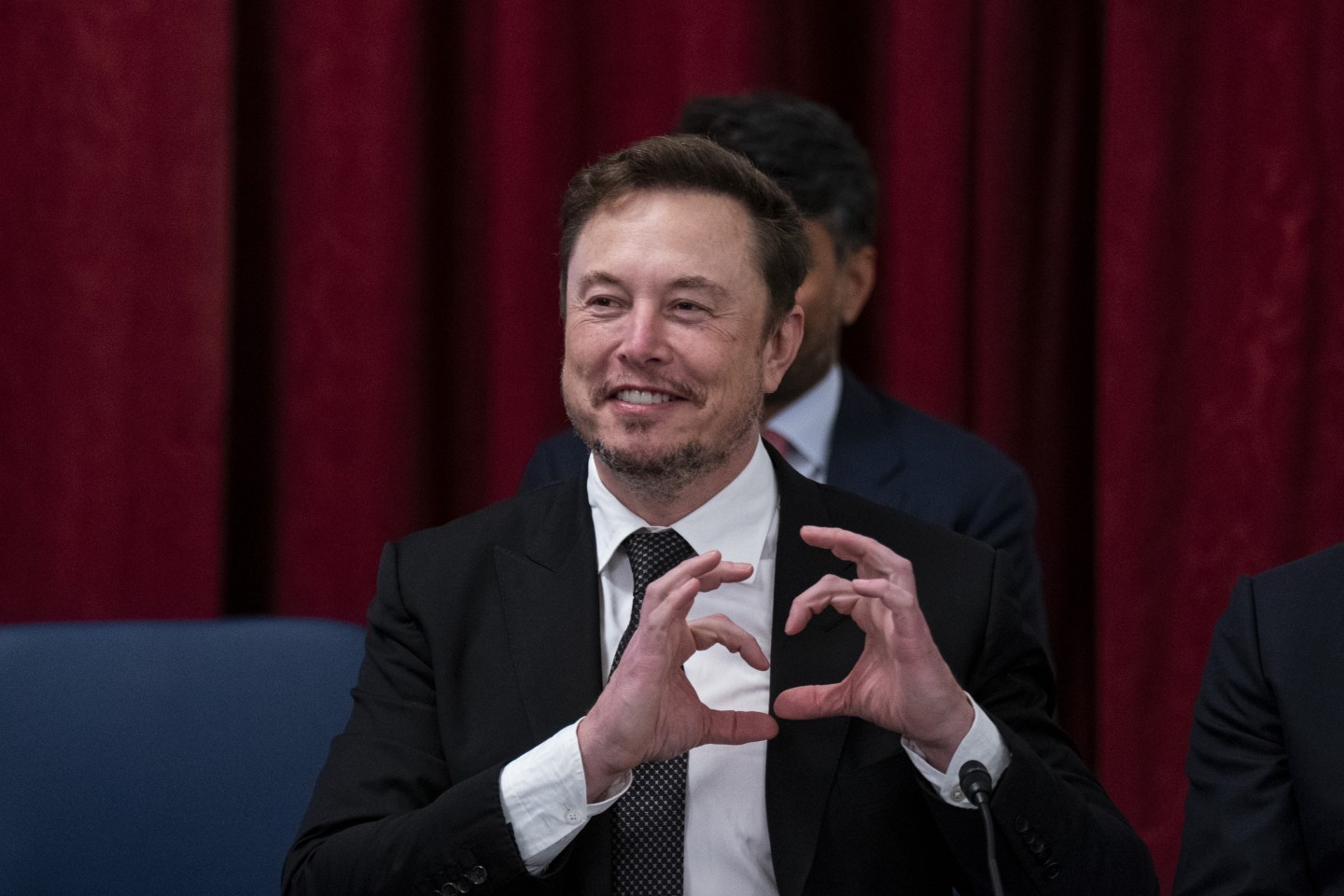 Elon musk making a heart with his hands.