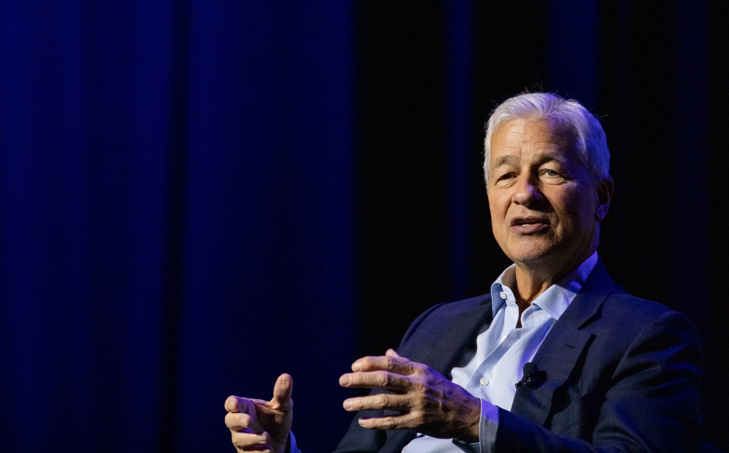 man in collard shirt and jacket speaking onstage