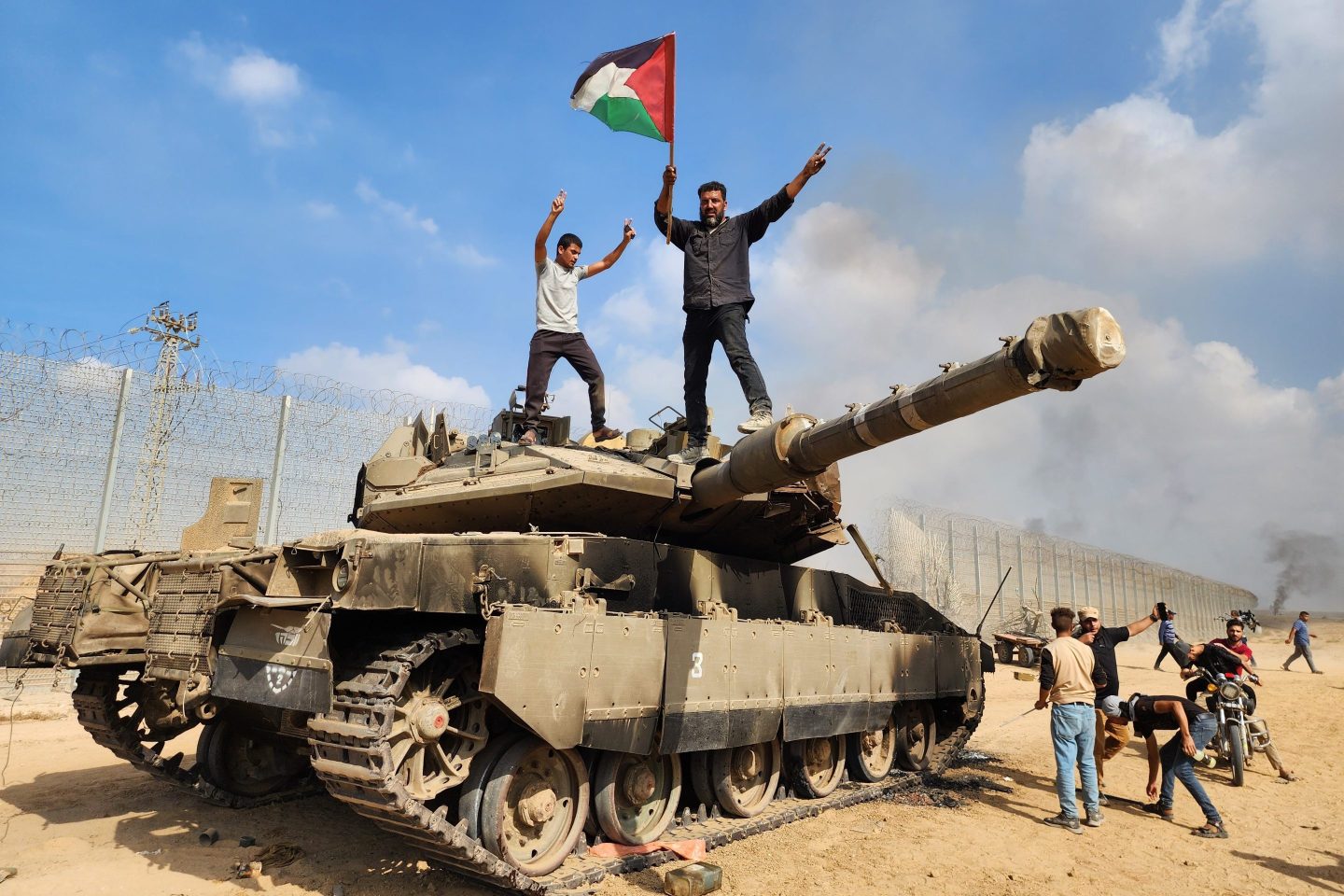 Members of Hamas’s armed wing, the Izz ad-Din al-Qassam Brigades, hold a Palestinian flag as they destroy a tank of Israeli forces in Gaza City, Gaza, on Oct. 7, 2023.
