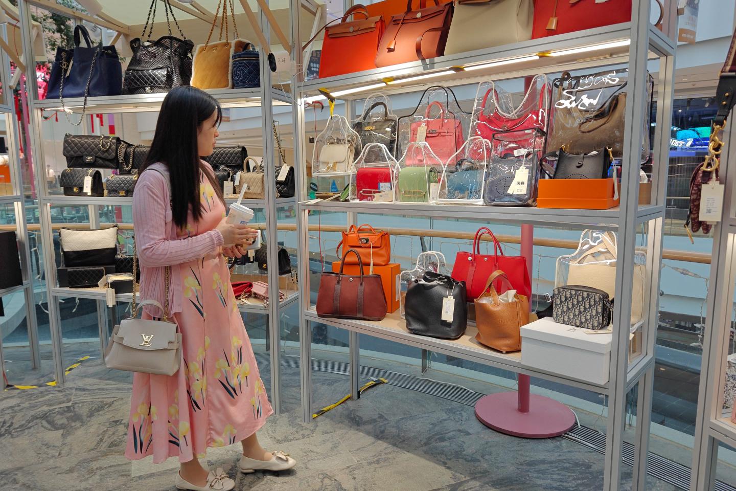 A lady looking at handbags on display in a second-hand luxury goods store at a shopping mall in Shanghai