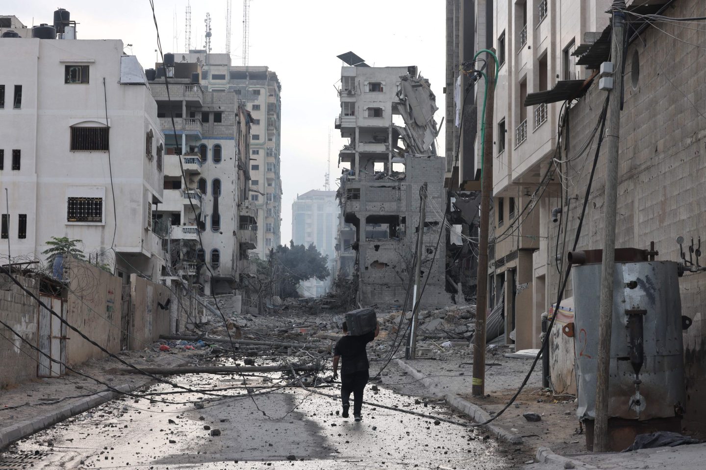 A Palestinian man walks past damaged buildings with a suitcase on his shoulders following Israeli airstrikes in Gaza City on Oct. 10, 2023. Israel kept up its deadly bombardment of Hamas-controlled Gaza after the Palestinian militant group threatened to execute some of the around 150 hostages it abducted in a weekend assault if air strikes continue.
