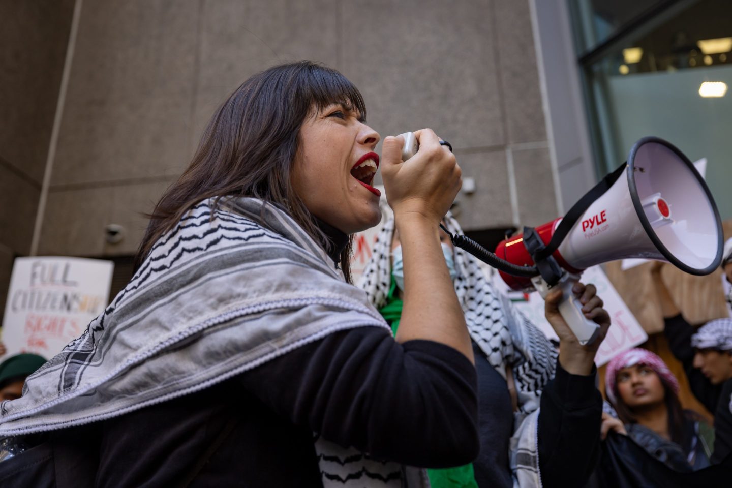 A college student with a bull horn leads a chant at a pro-Palestinian demonstration