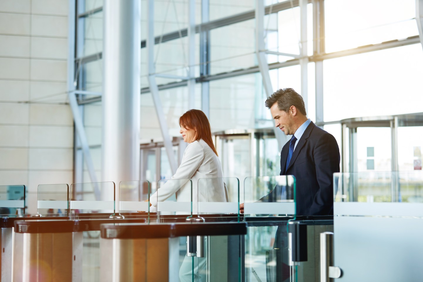 Two people entering their office building through security turnstiles