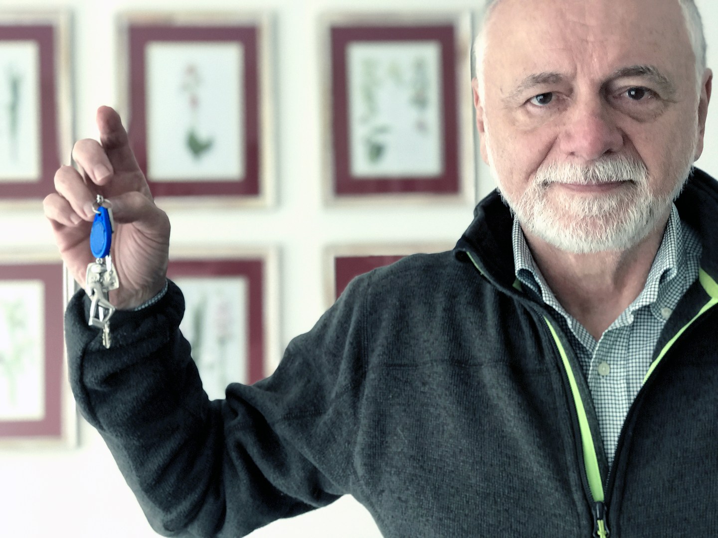 Man with gray hair and beard holds up a set of keys