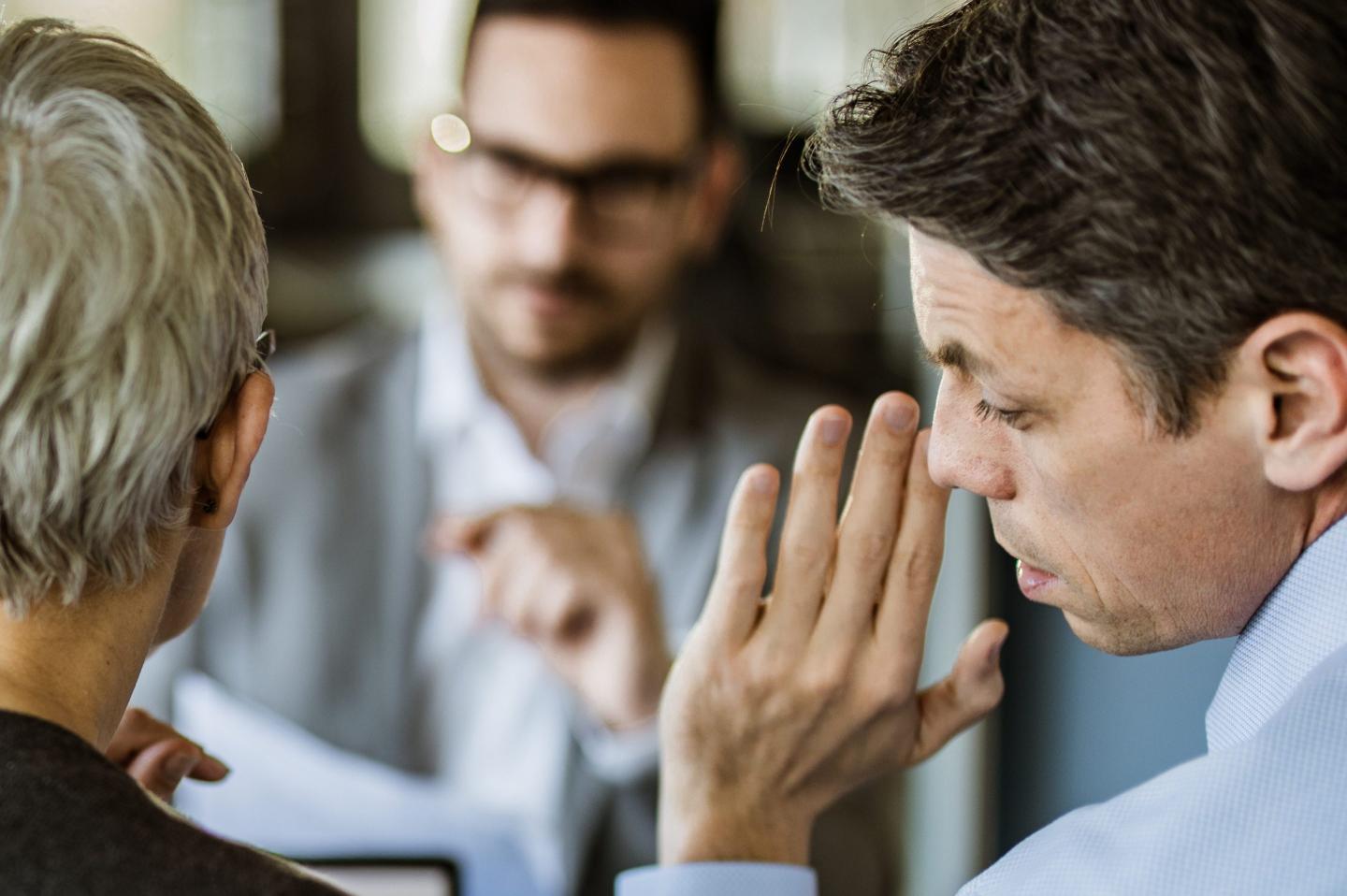 Executives in a meeting whisper to each other