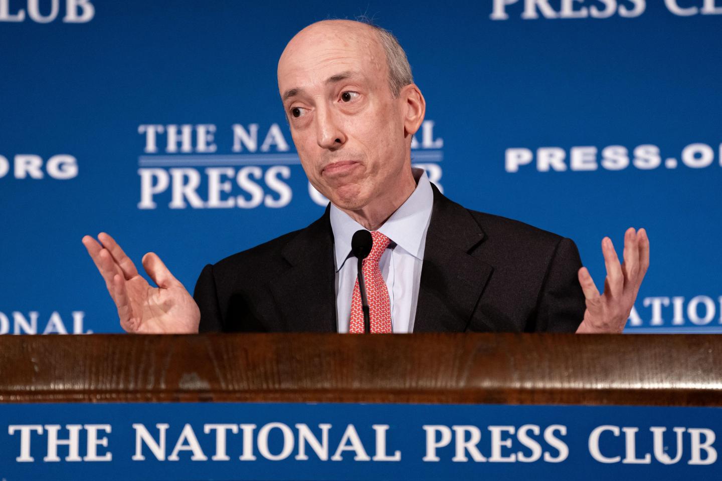 man in suit and tie standing in front of a podium