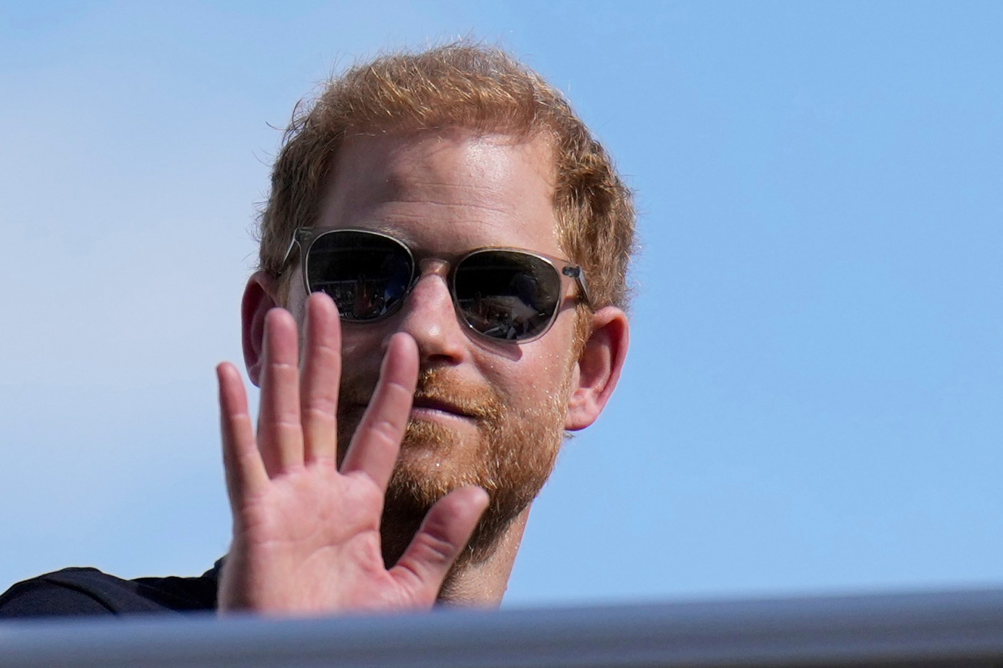 Prince Harry wearing sunglasses and waving
