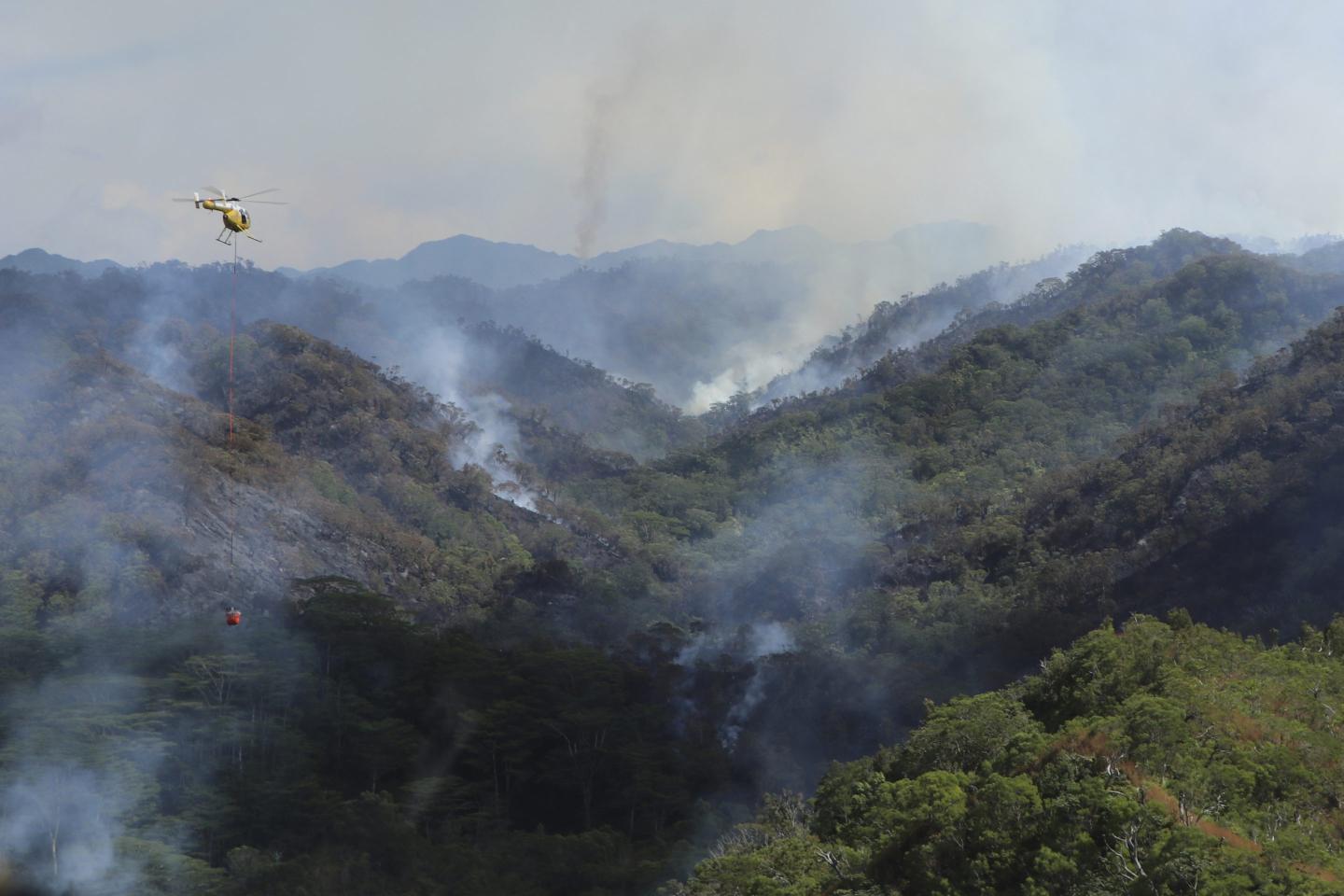 An Army helicopter carrying water to douse a wildfire burning east of Mililani, Hawaii,