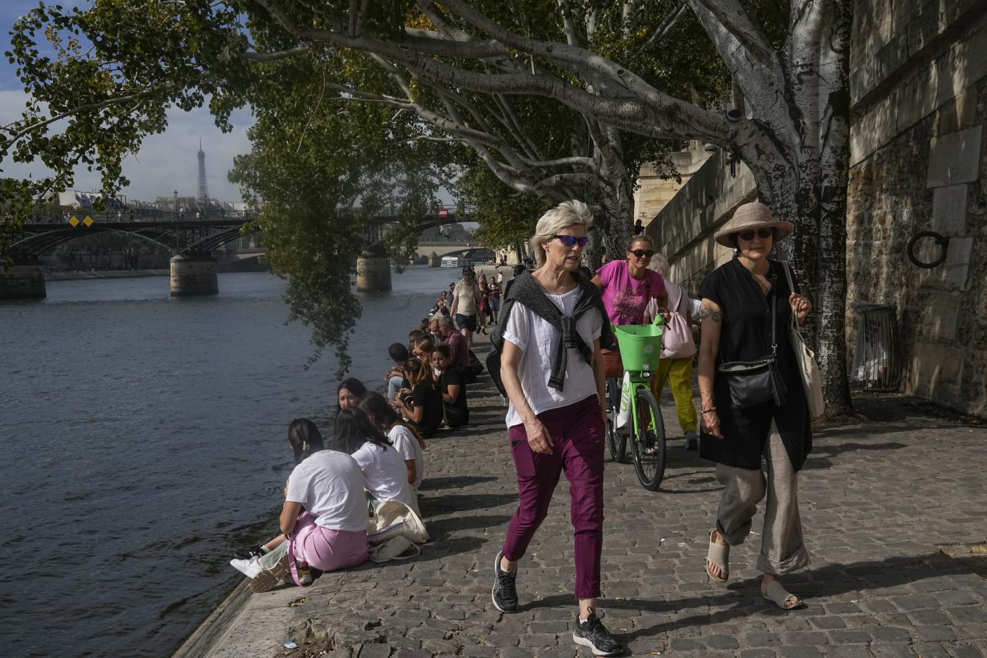 People walk along the Seine River, Oct. 2, 2023, in Paris where temperatures rose.