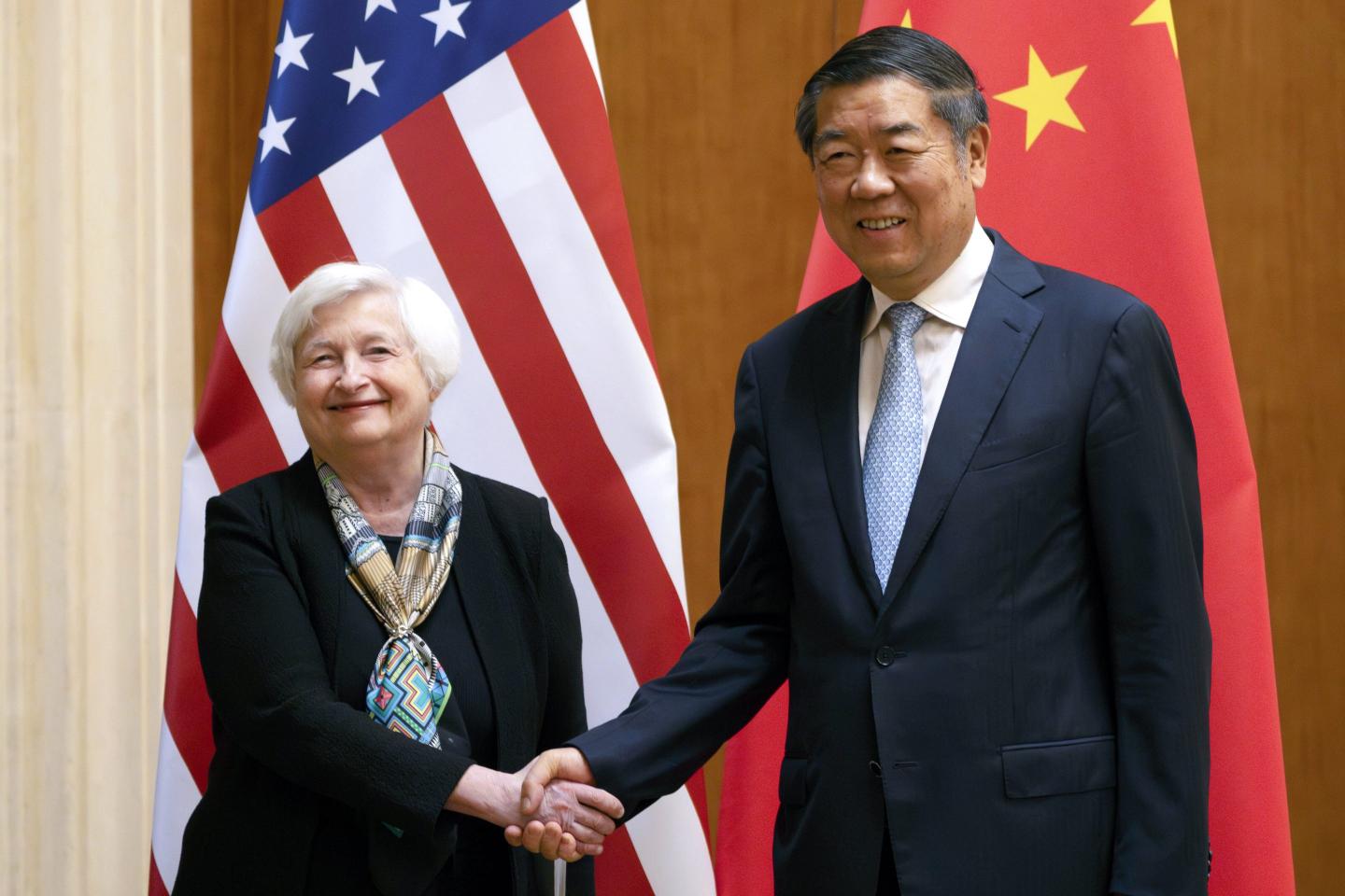 Treasury Secretary Janet Yellen, left, shakes hands with Chinese Vice Premier He Lifeng while standing in front of their respective country's flag
