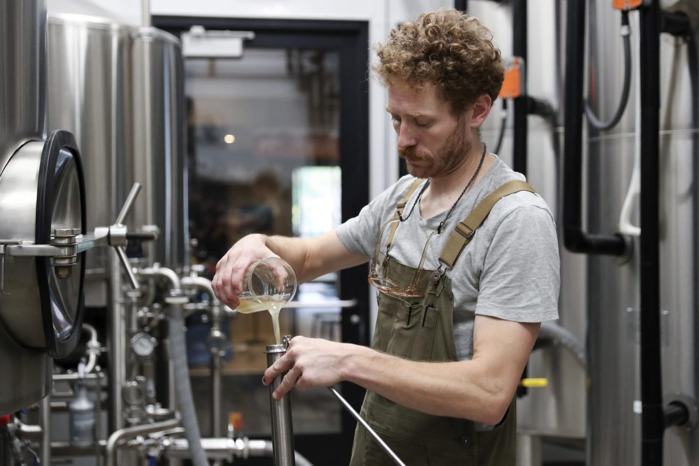 A brewer measures out a sample of wort while brewing a German-style Pilsner