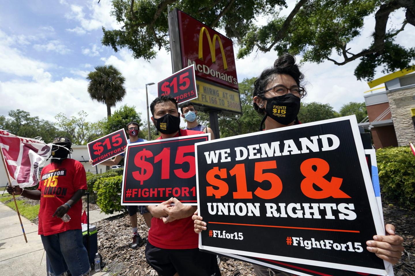 People picketing in front of a McDonald's holding signs that read, "We demand $15 & union rights."