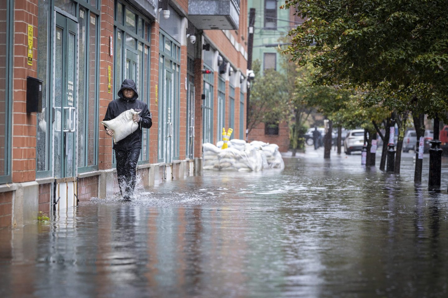 A person carries sand bags through a flooded street