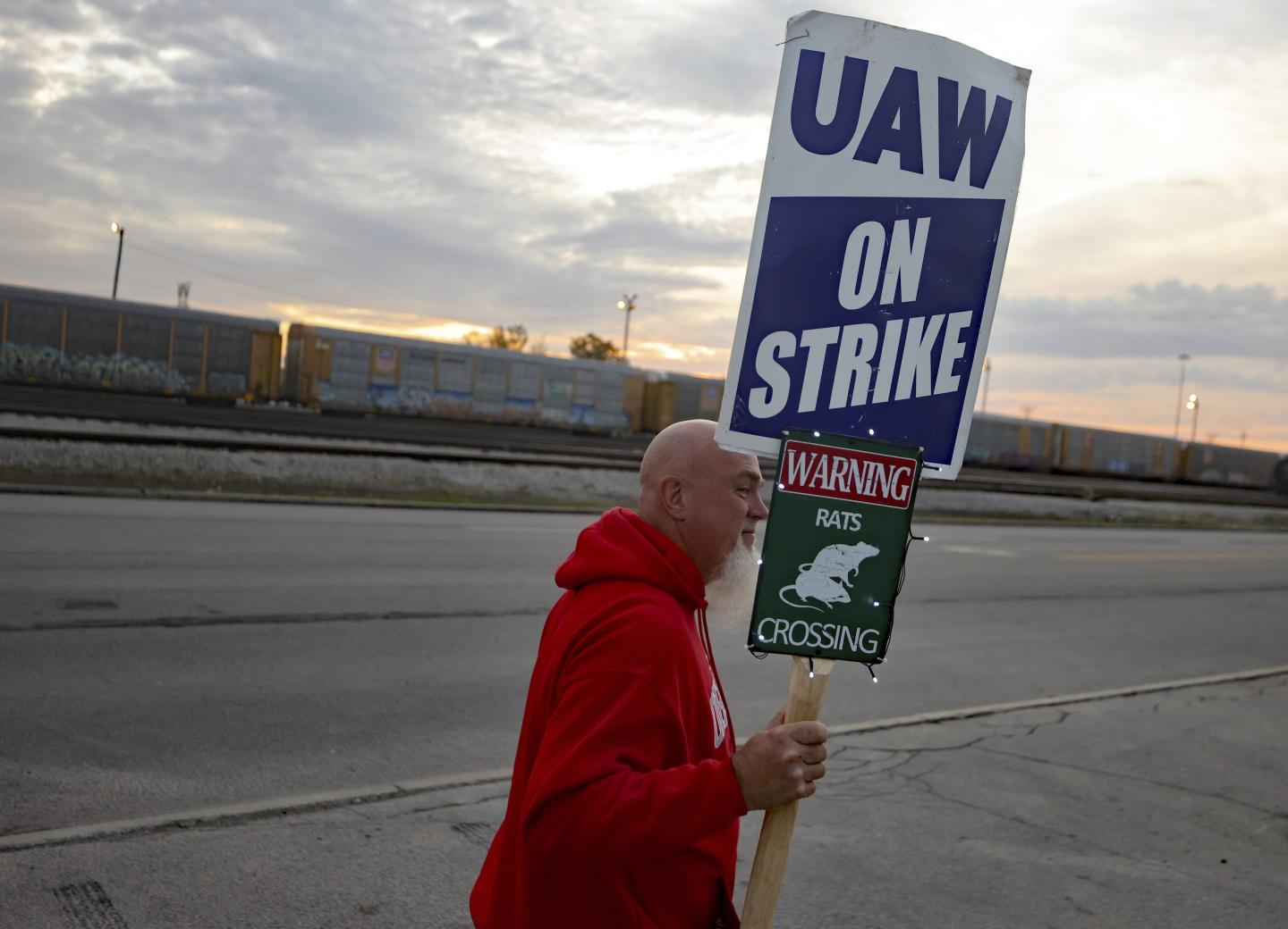 A UAW autoworker picketing in front of a Stellantis assembly plant