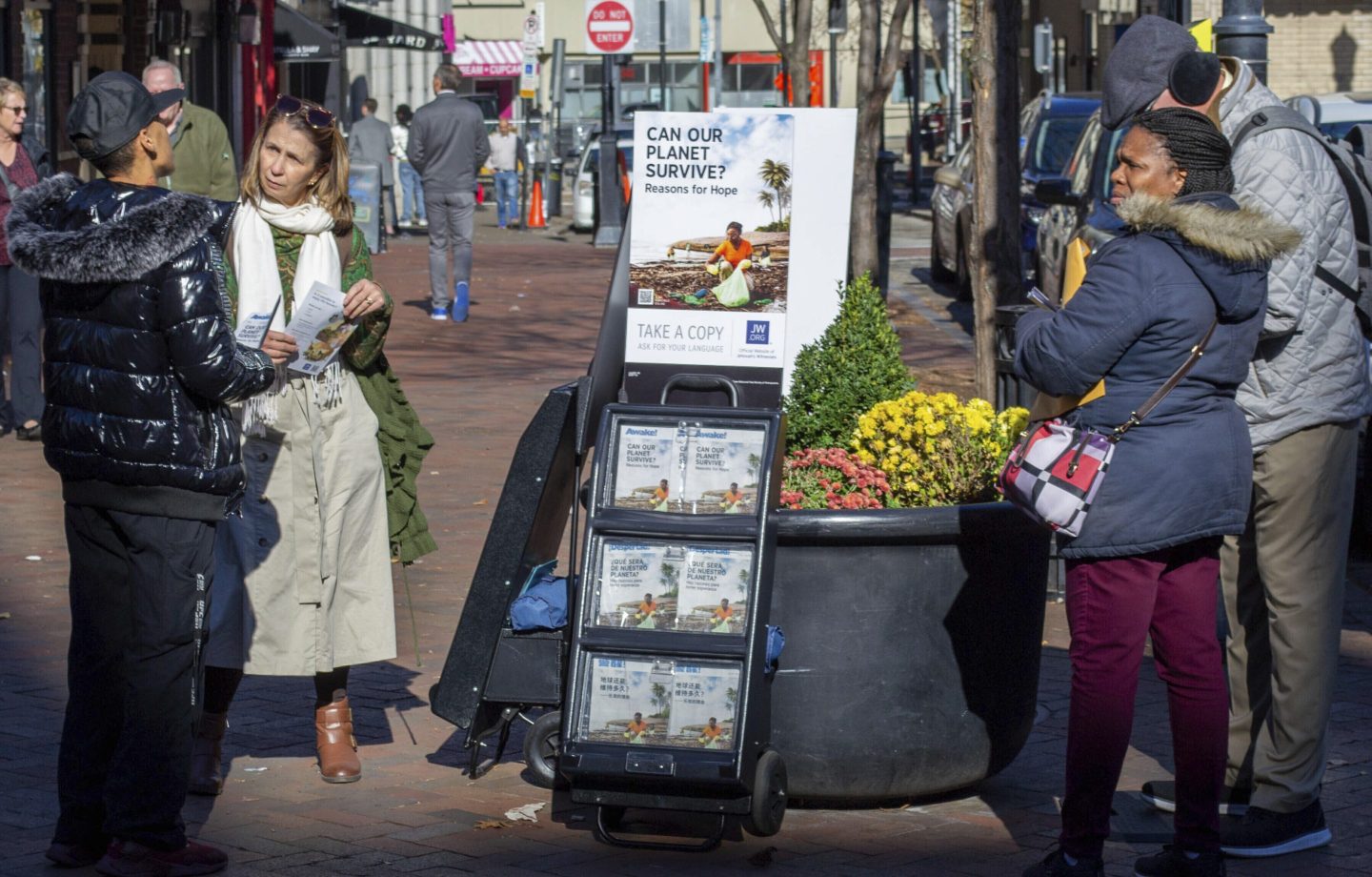 A woman shares Jehovah's Witnesses' literature with a passerby in downtown Pittsburgh on Monday, Nov. 13, 2023.