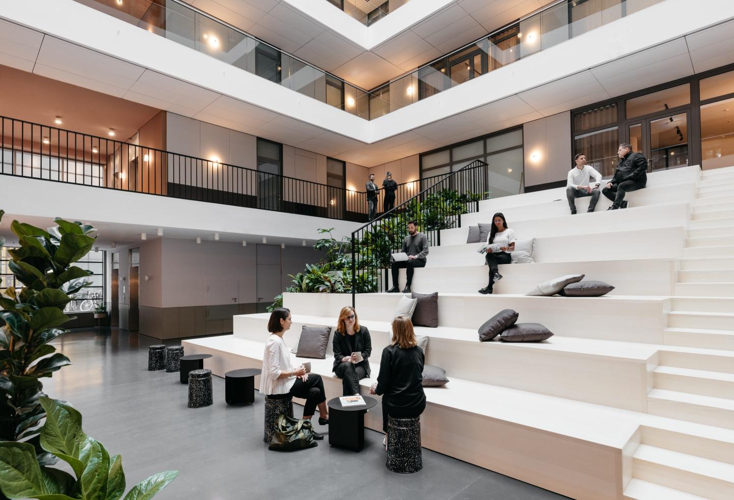 people sitting in a well lit room on white stairs