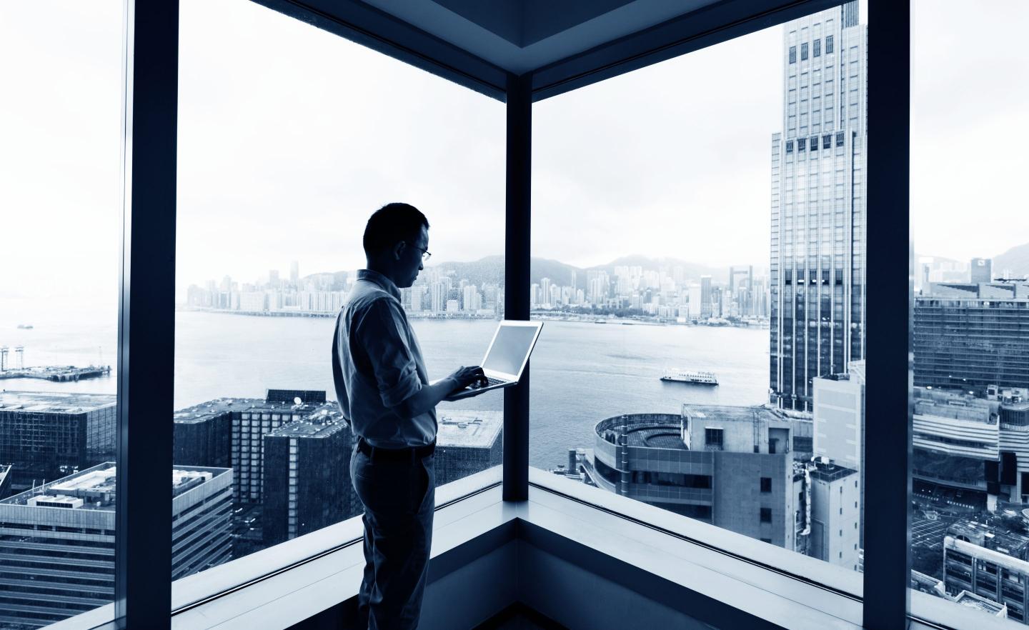 Businessman standing by the window and using laptop