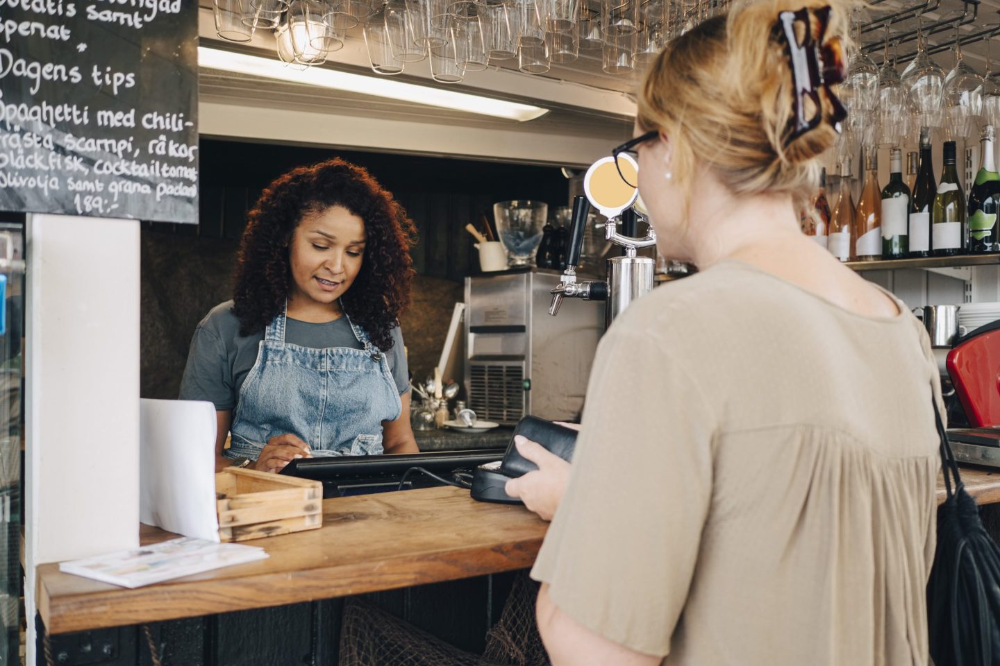 Business owner receiving payment from a female customer at a restaruant.