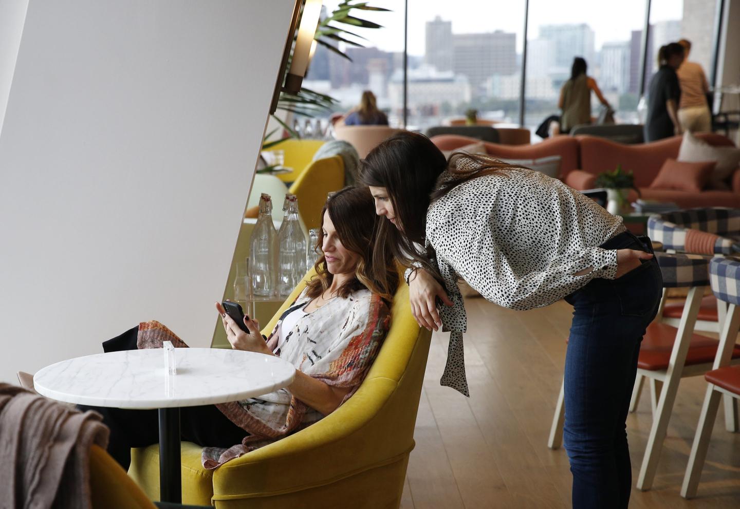 two women sit in an open office area