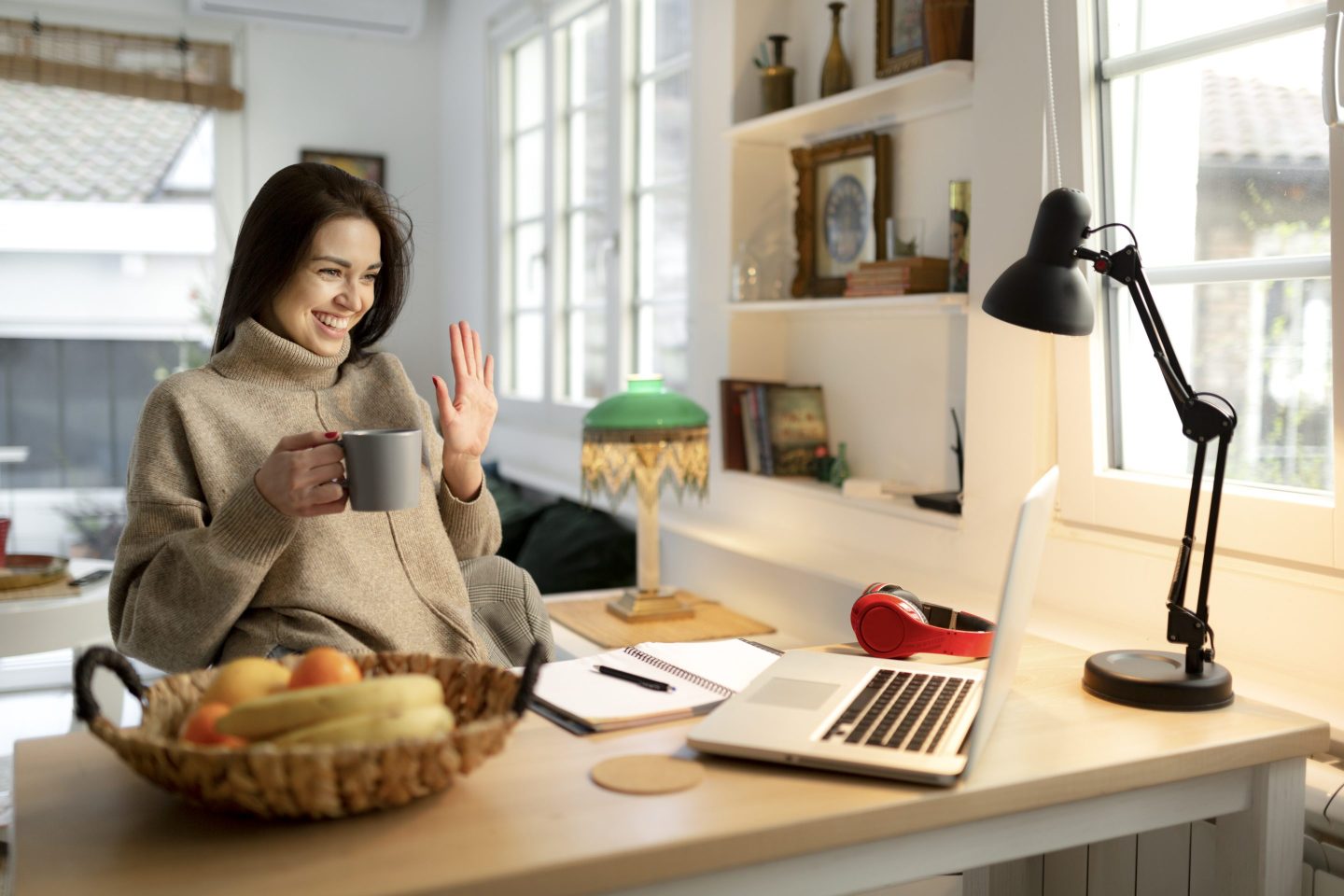 woman smiling and waving at her monitor