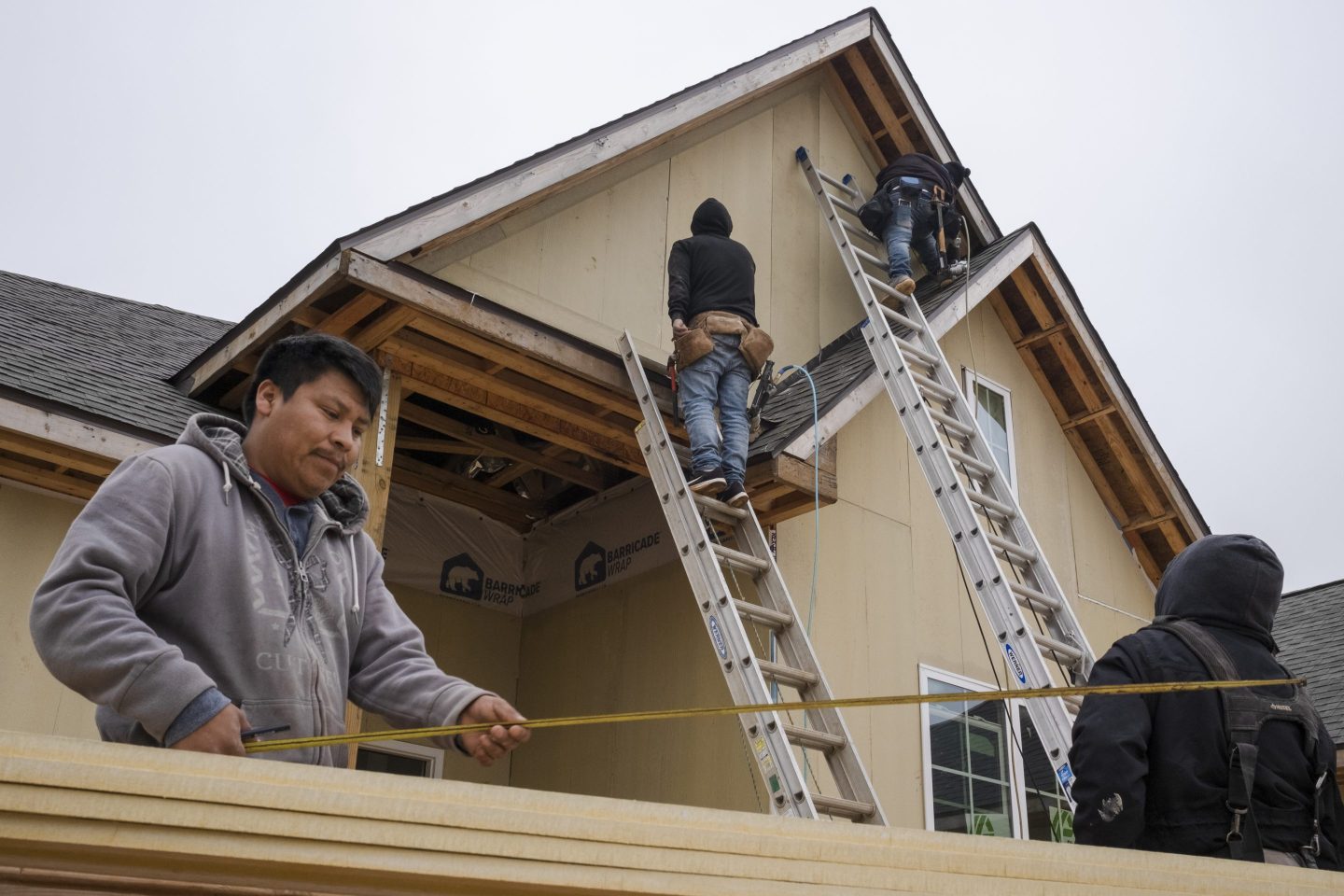 Construction workers cut and apply trim to the roof of a new home in Foley, Alabama, US, on Wednesday, Dec. 21, 2022.