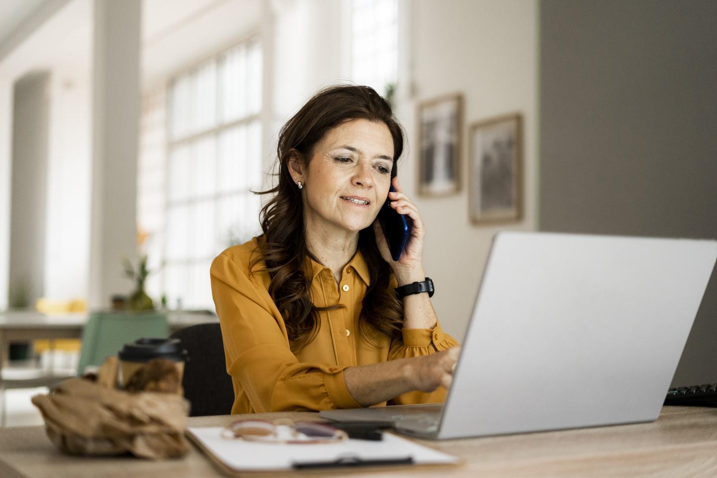 woman talking on the phone and looking at her laptop