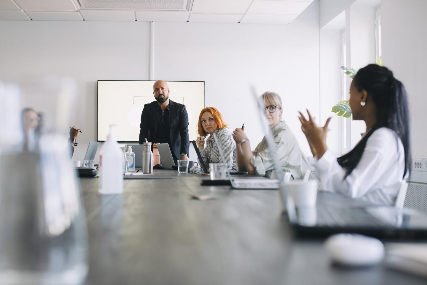 Businesswoman sharing ideas with male and female colleagues in board room.