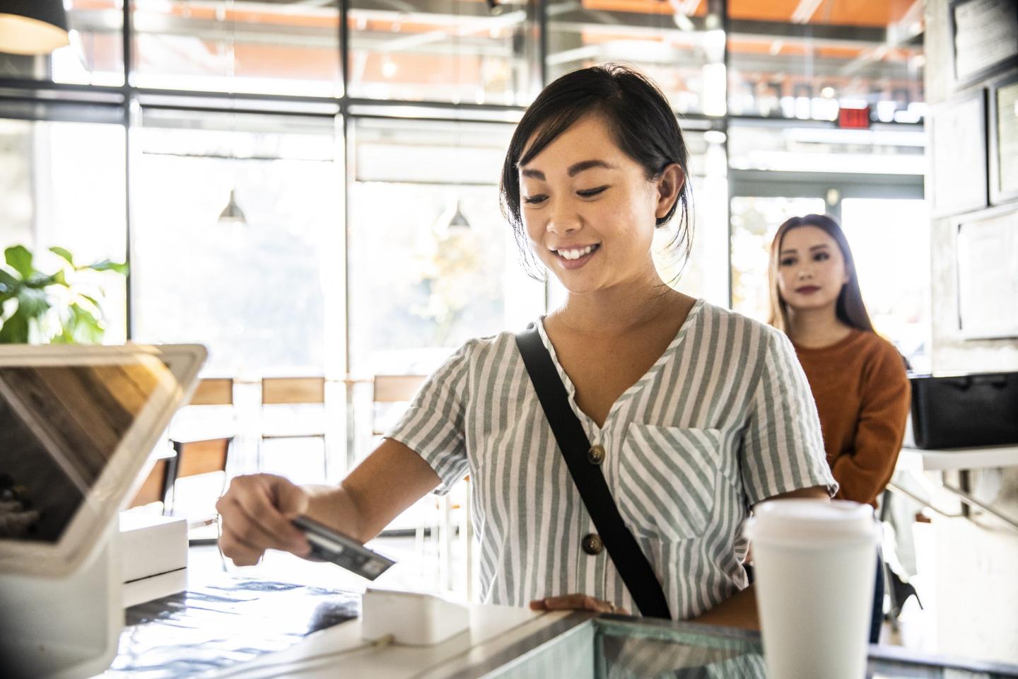 Young woman using credit card reader at coffee shop counter