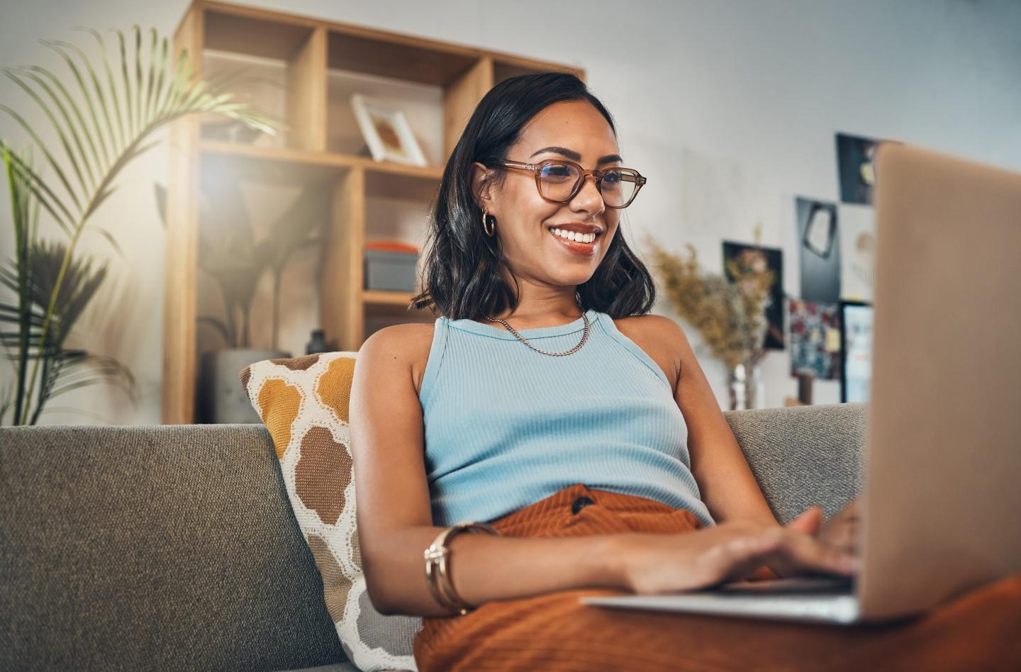 Smiling mixed race woman browsing internet on a laptop at home.