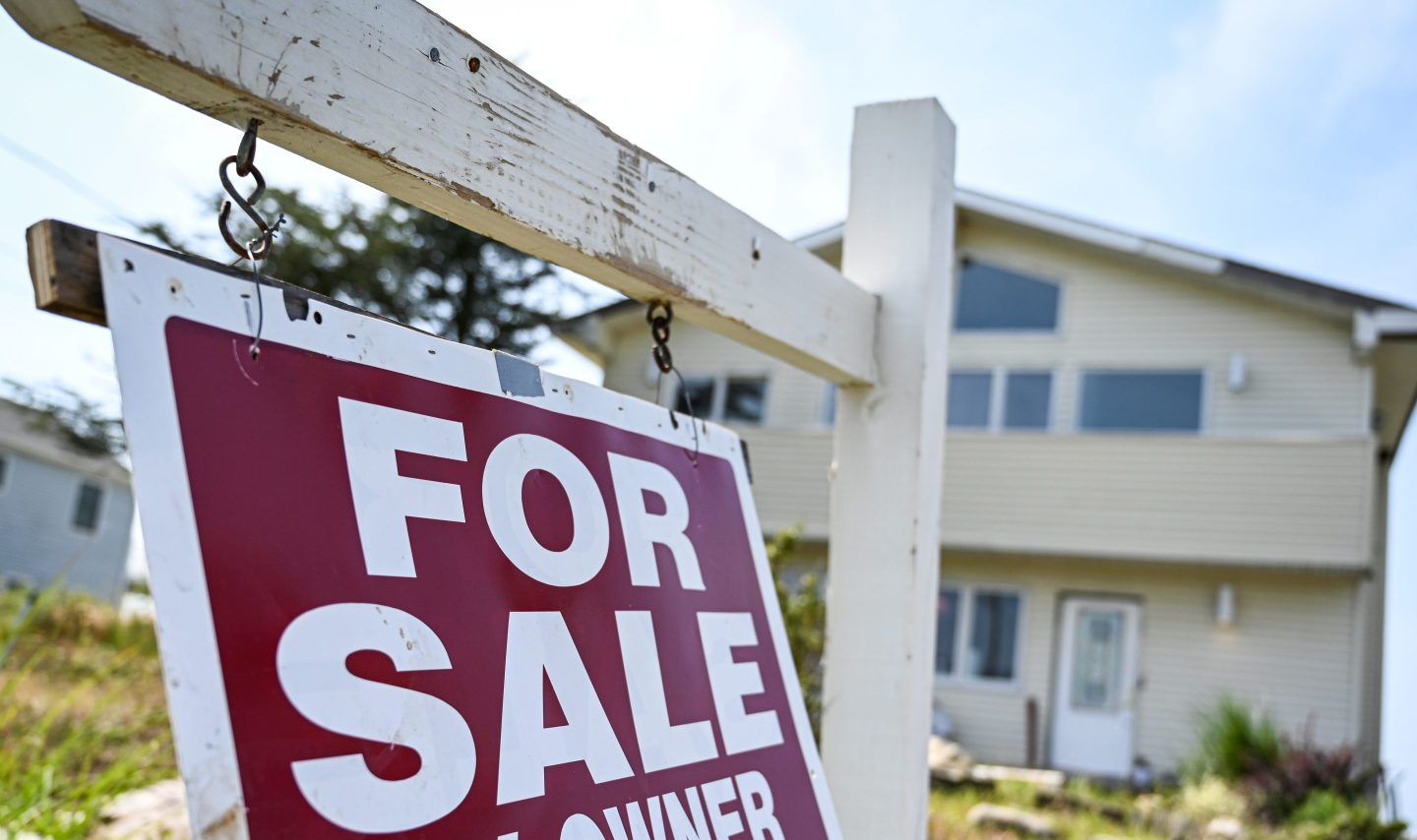 "For sale" sign hangs in front of a house