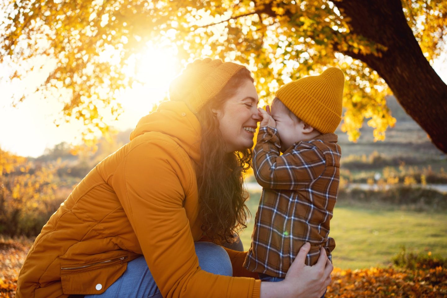 Caucasian mother and her toddler son enjoy the autumn day in the nature.