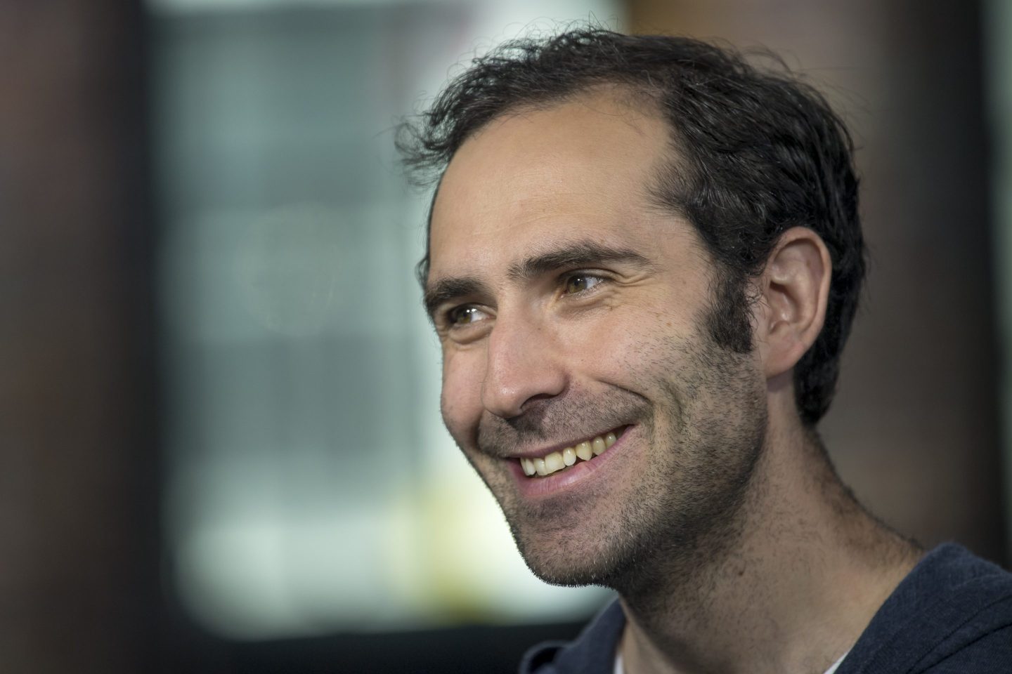 A close up shot of Emmett Shear smiling during a Bloomberg Television interview.