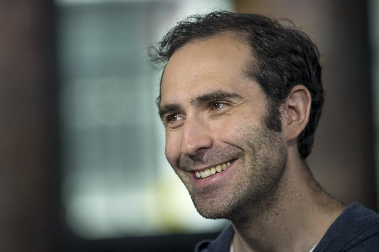 A close up shot of Emmett Shear smiling during a Bloomberg Television interview.