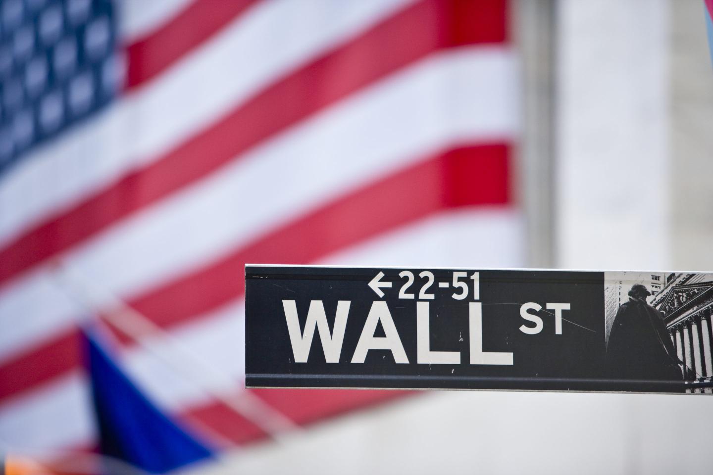 Wall Street sign, with a giant American flag in the background.