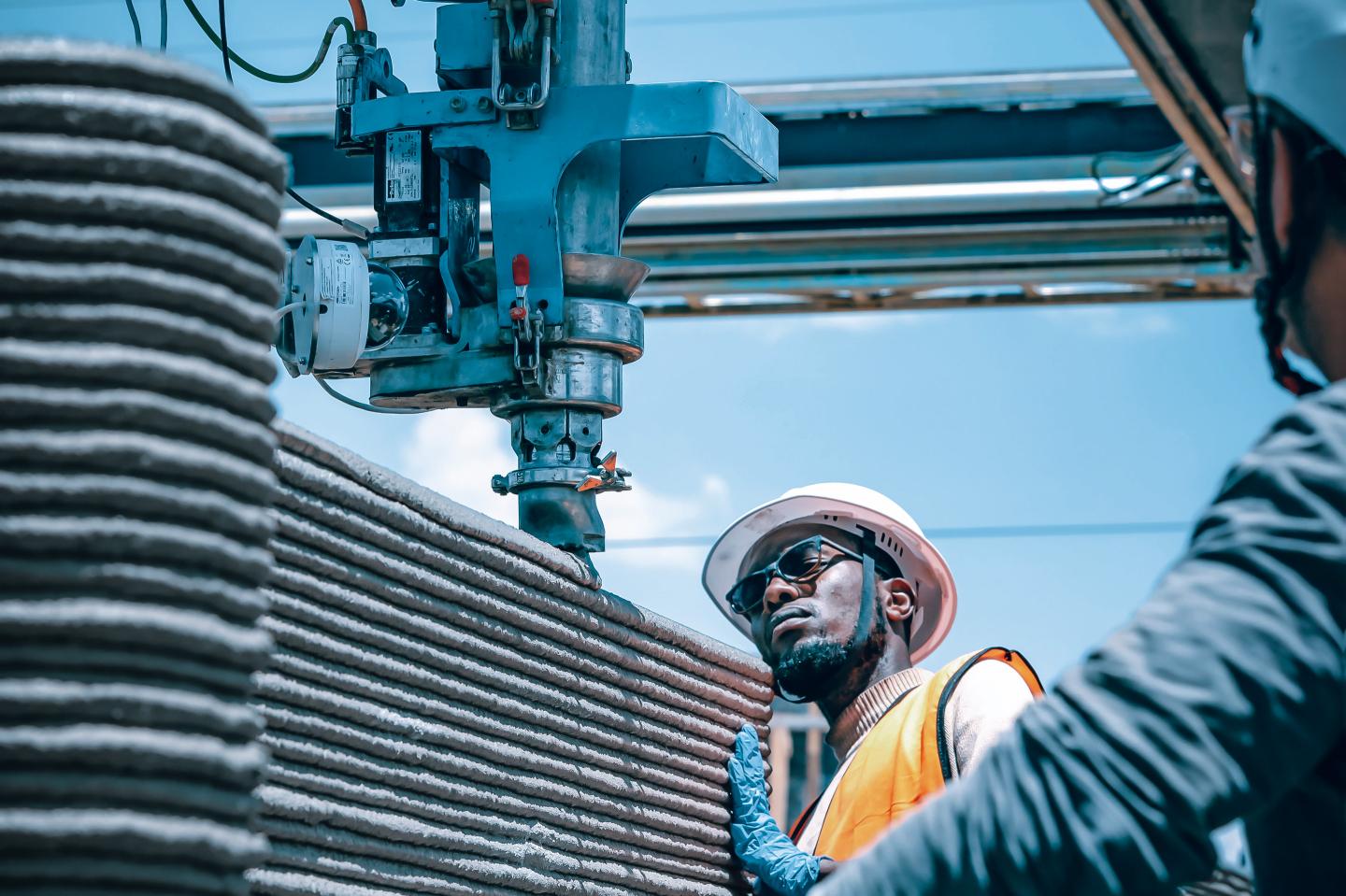 Employees using 3d-printed cement on a housing development in Kenya.