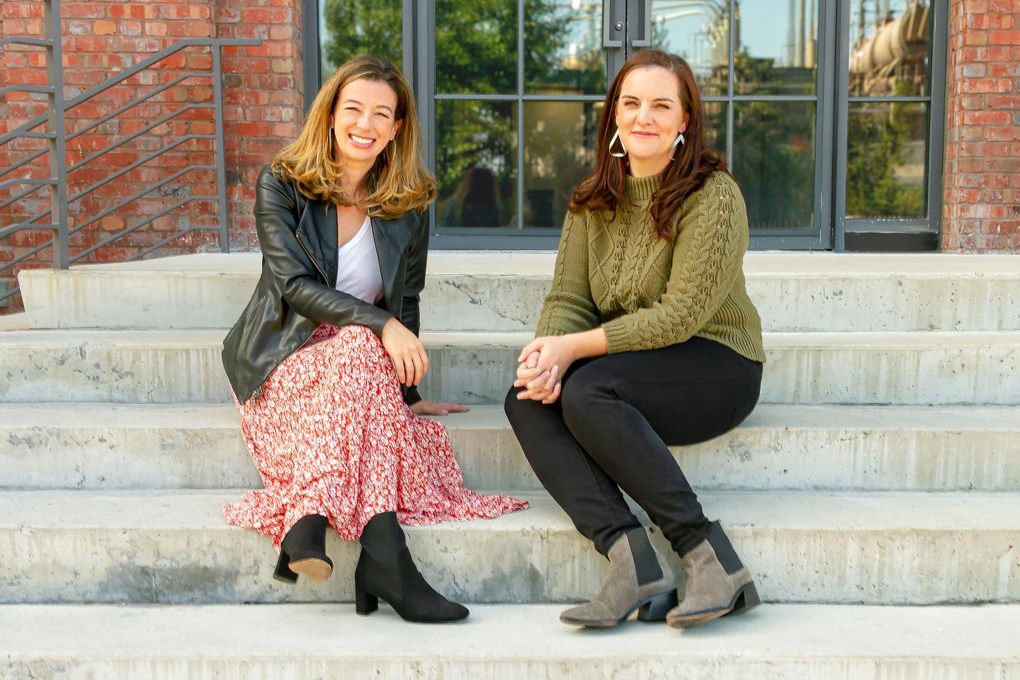 two women sitting on concrete steps, posing for a photograph