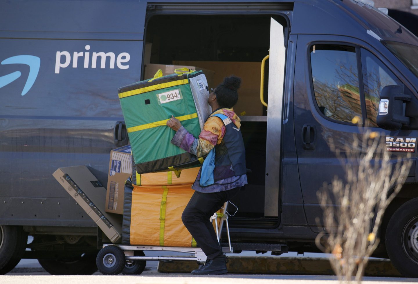 An Amazon Prime delivery person lifts packages while making a stop at an apartment building on Nov. 28, 2023, in Denver.