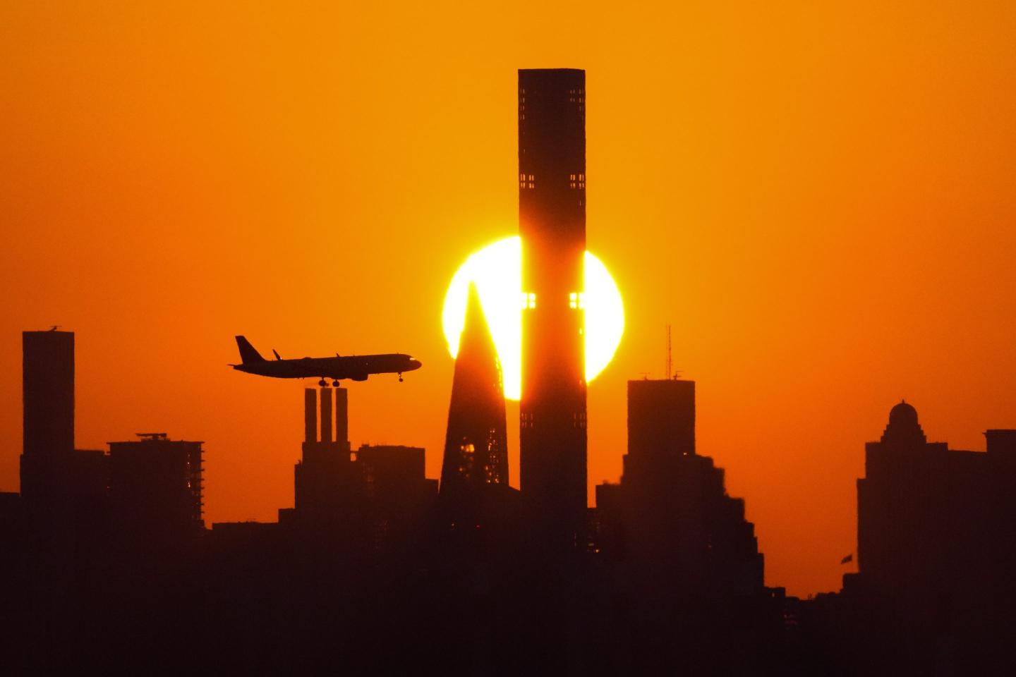 The sun sets behind the Manhattan skyline as plane approaches LaGuardia Airport on Sept. 6, 2023, in New York.