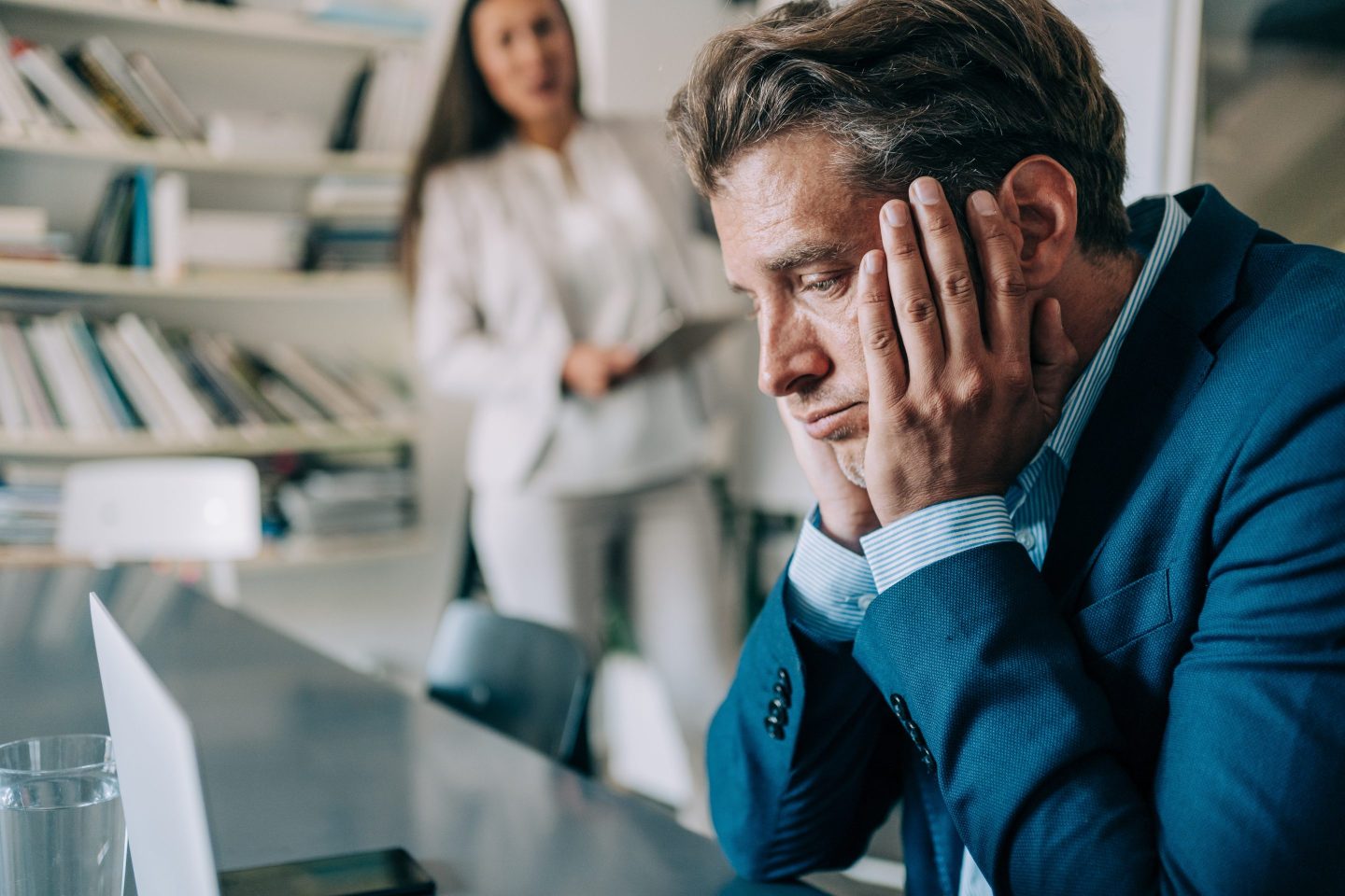 Overworked businessman in a blue suit sitting in the board room