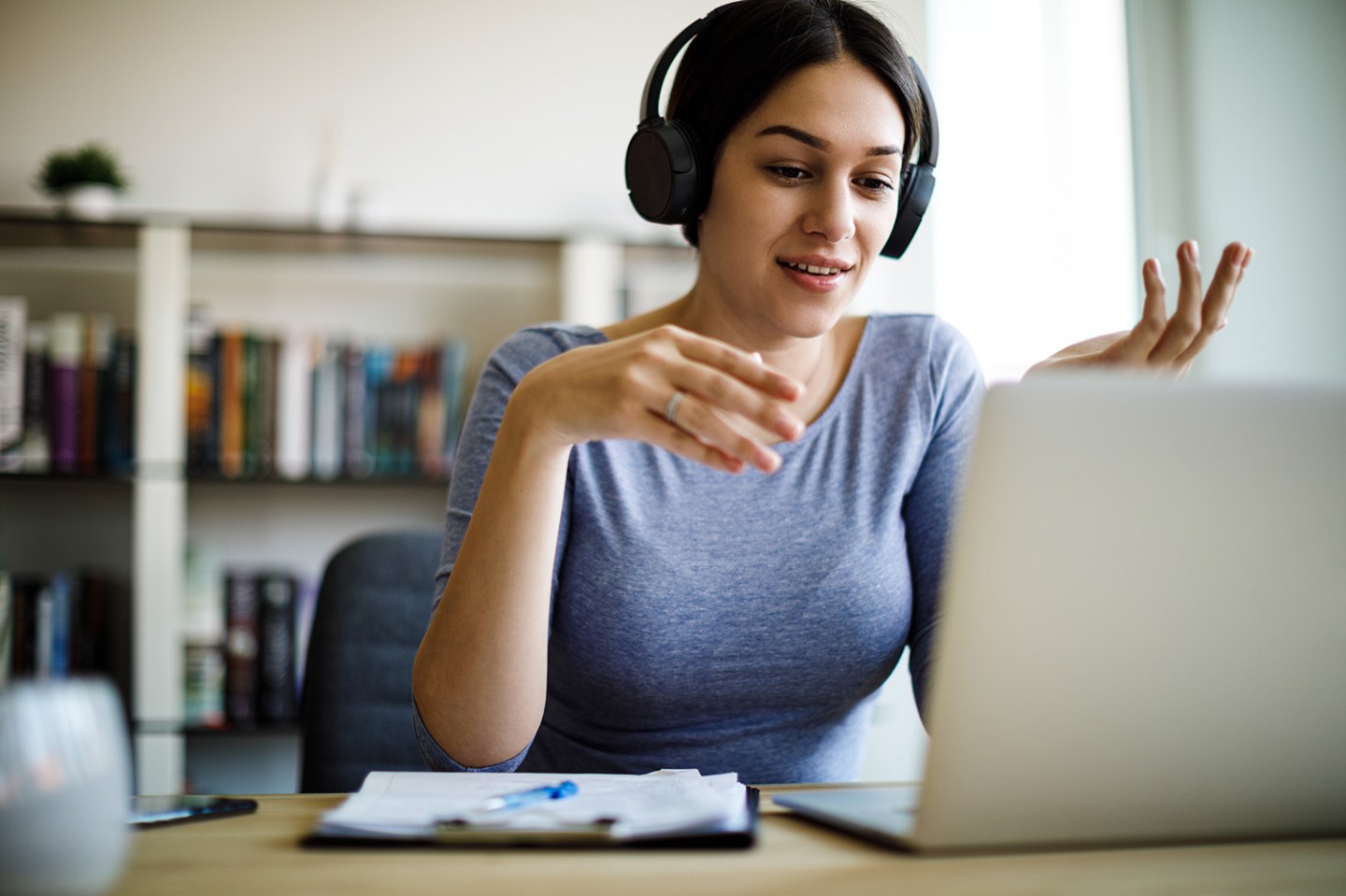 Photo of a woman sitting in front of her laptop working with headphones on