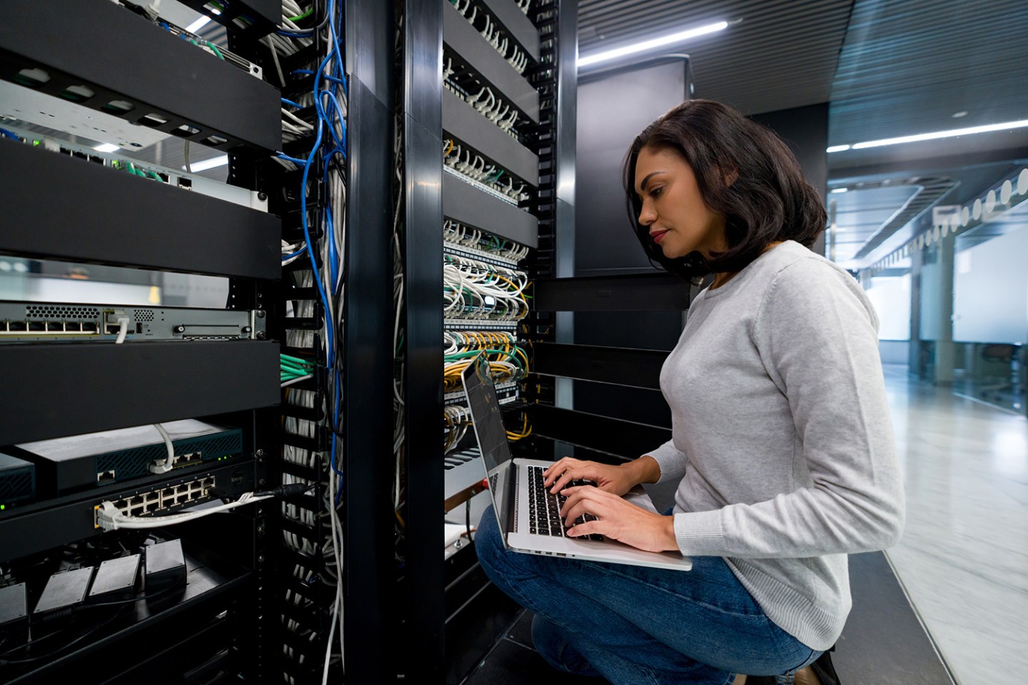 Female IT support technician fixing a network server at an office - technology concepts