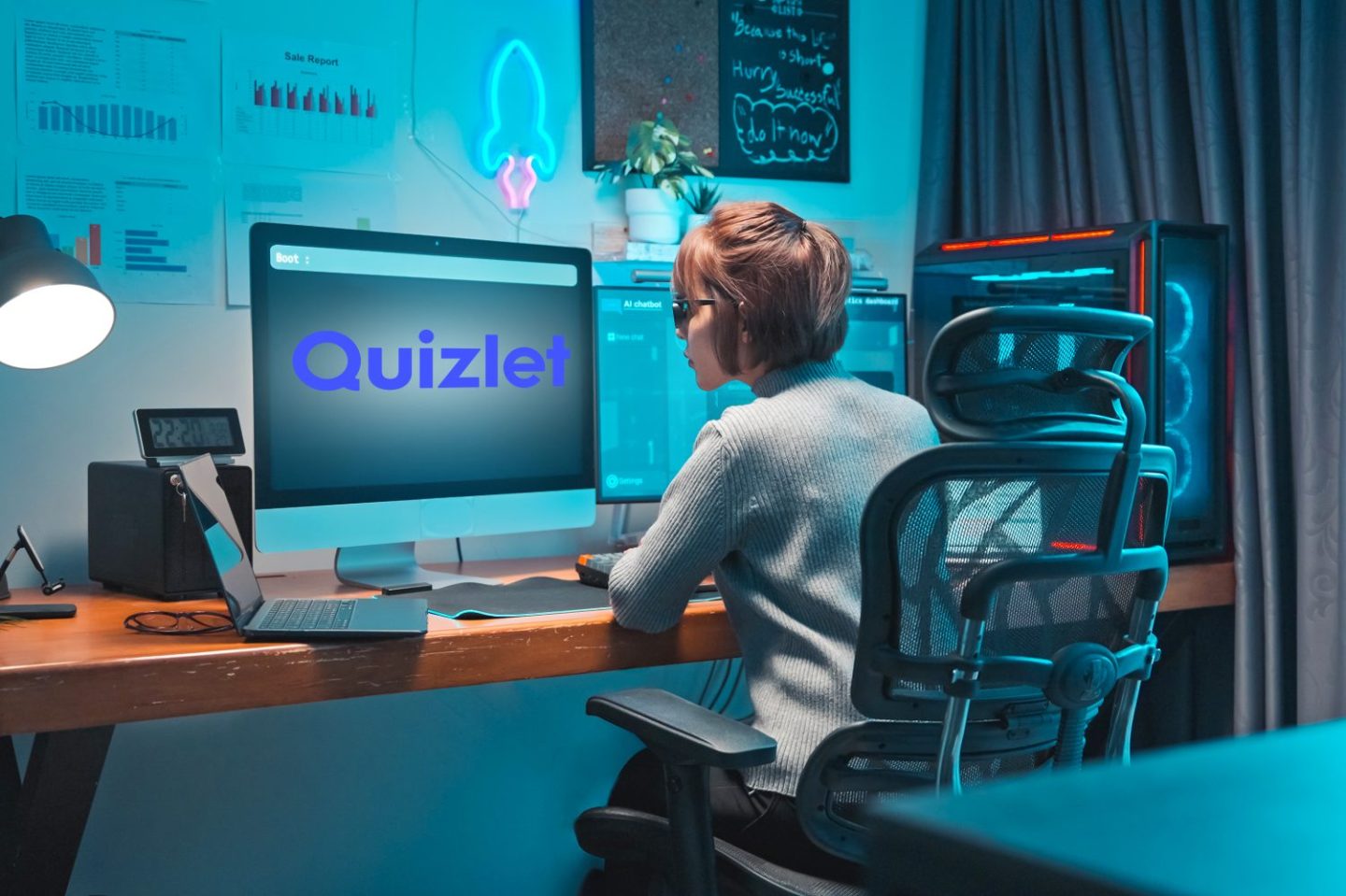 Photo of a young woman working in AI at her desk in front of a computer monitor with the Quizlet logo on it.