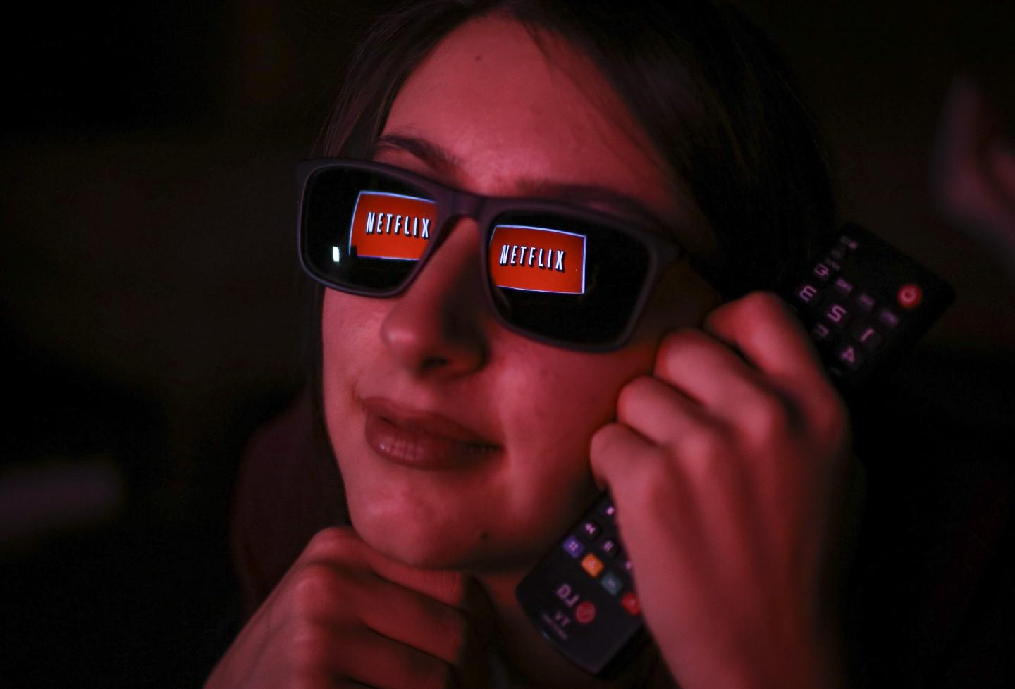 Netflix logo is reflected on a woman's eye glasses