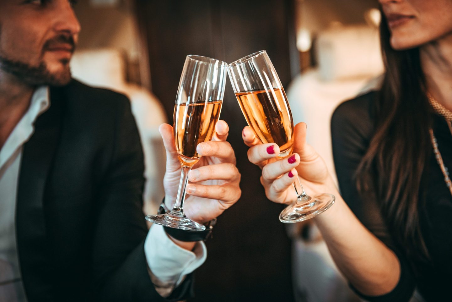 A close-up of a rich, well-dressed couple having a toast with champagne while traveling in a private jet