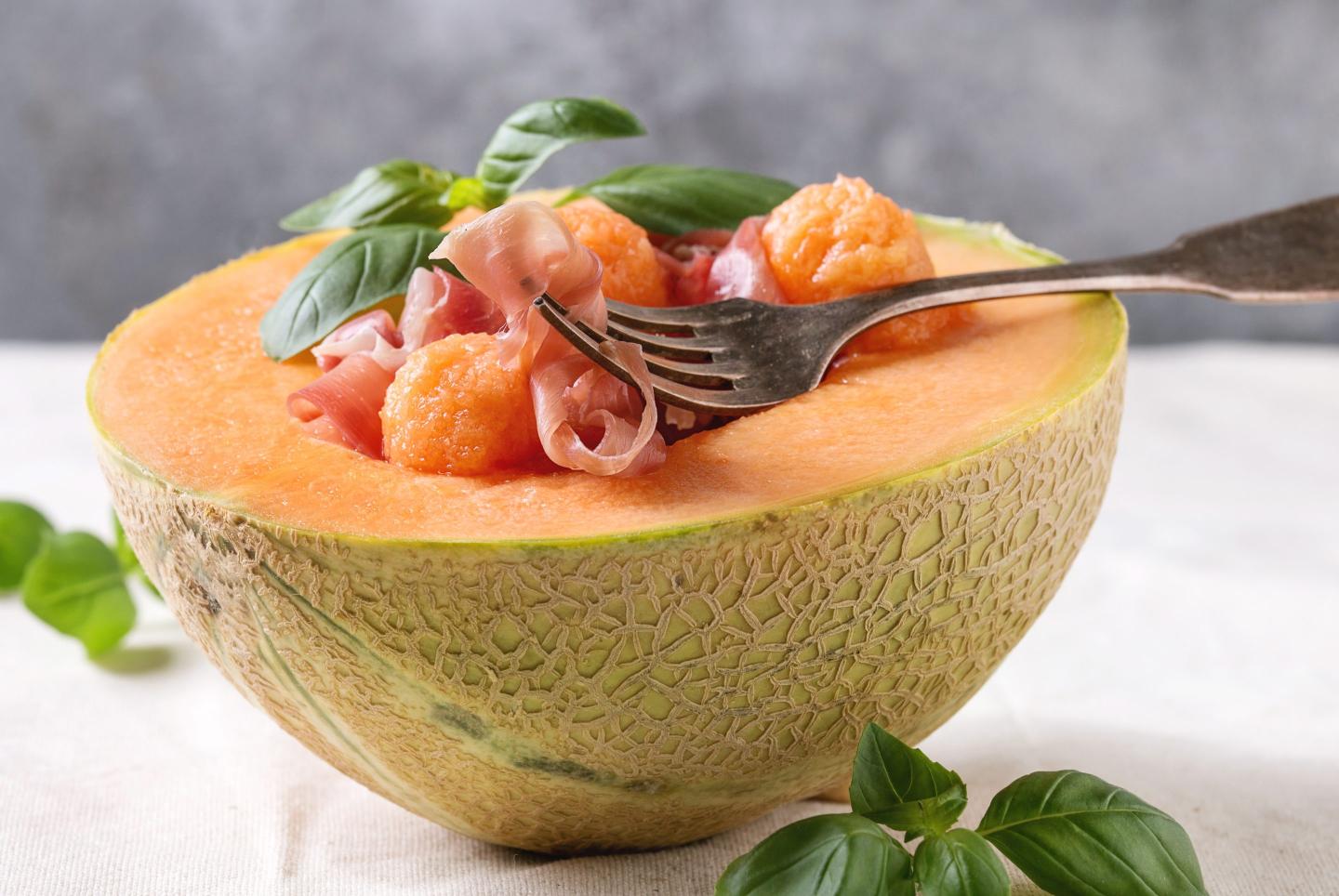 Melon and ham or prosciutto salad served in half of Cantaloupe melon