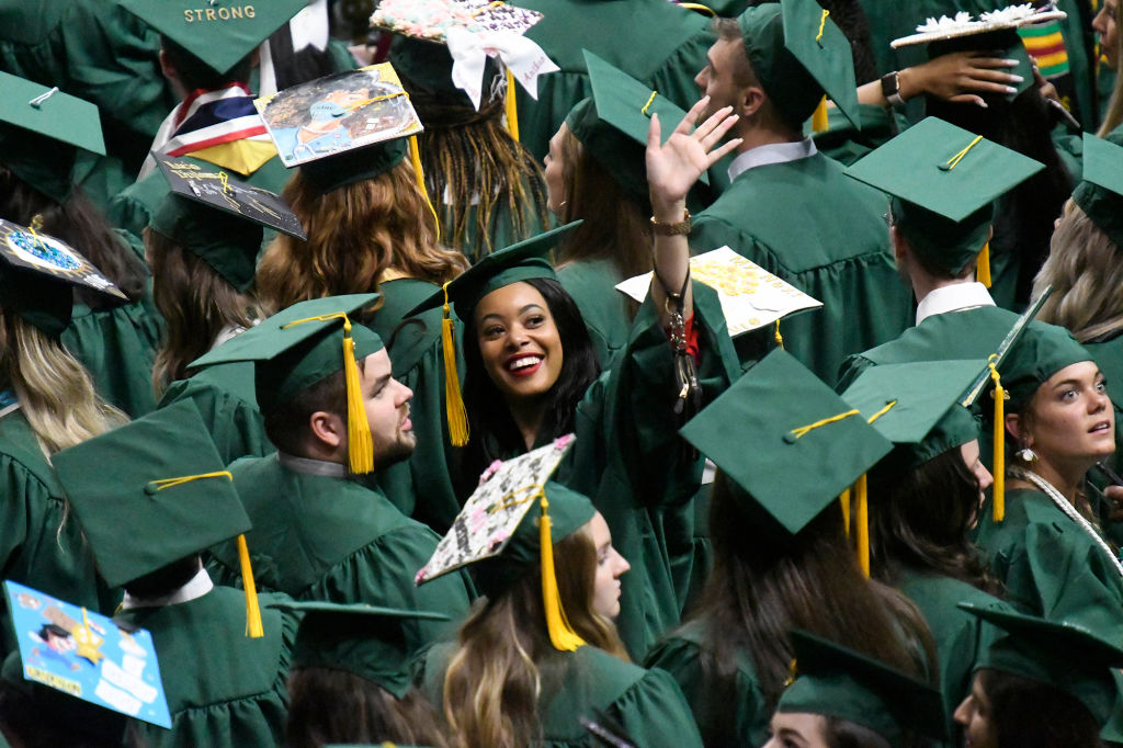 UNC Charlotte graduating seniors wave to friends and family during the College of Liberal Arts & Sciences commencement ceremony at Halton Arena in Charlotte, N.C., as seen in May 2019. (David T. Foster III—Charlotte Observer/Tribune News Service/Getty Images)
