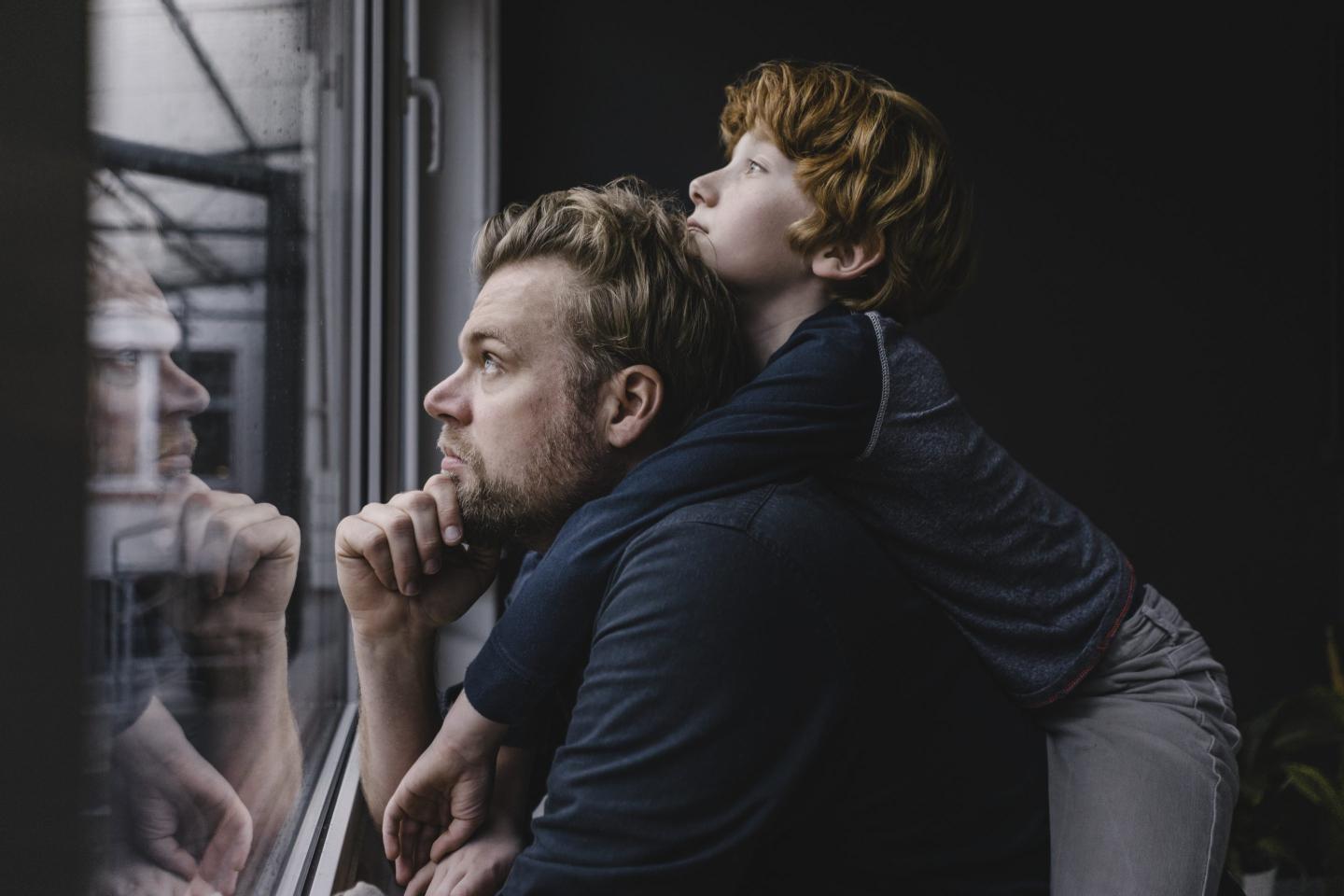 Father and young son looking out a window