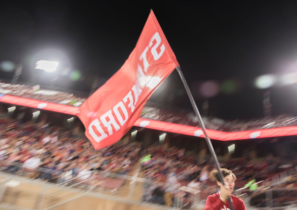 A Stanford cheer leader runs with the flag following a Stanford Cardinal score during an NCAA Pac-12 college football game against the Washington Huskies, as seen in October 2019 at Stanford Stadium in Palo Alto, California. (Photo by David Madison/Getty Images)