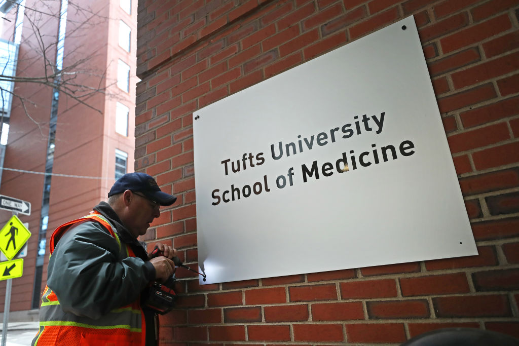 Scott Suleski with Sign Design & Sales attaches a new sign on the Tufts University building in Boston, as seen in December 2019. (Photo by David L. Ryan—The Boston Globe/Getty Images)